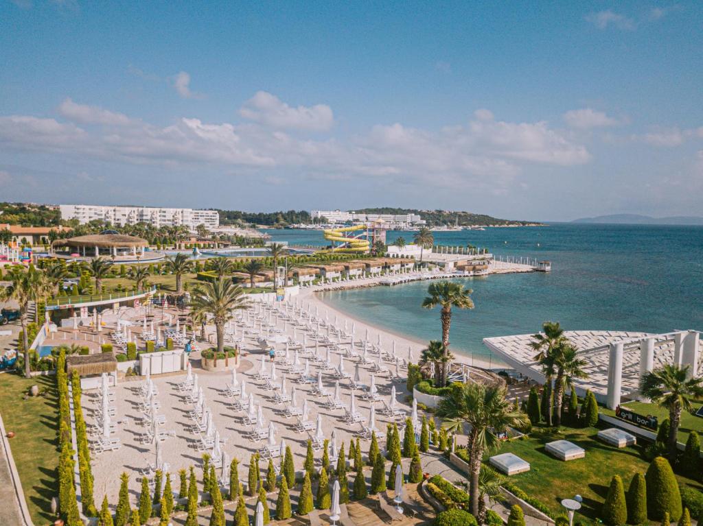 a beach with chairs and umbrellas and the ocean at Ilica Hotel Spa & Wellness Resort in Çeşme