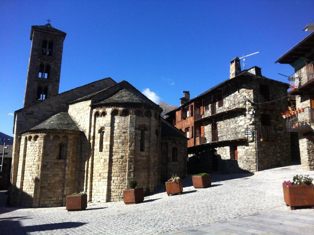 un antiguo edificio de piedra con una torre y una iglesia en Ca la Roia, en Taüll