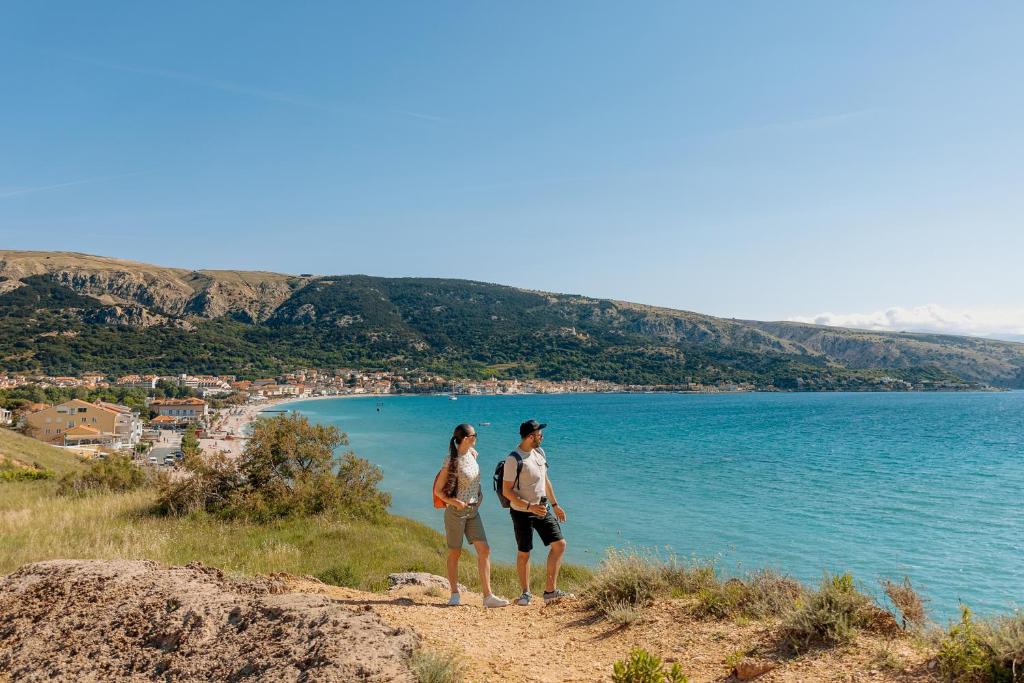 two people standing on a hill overlooking a body of water at Hotel Dobrovit in Baška