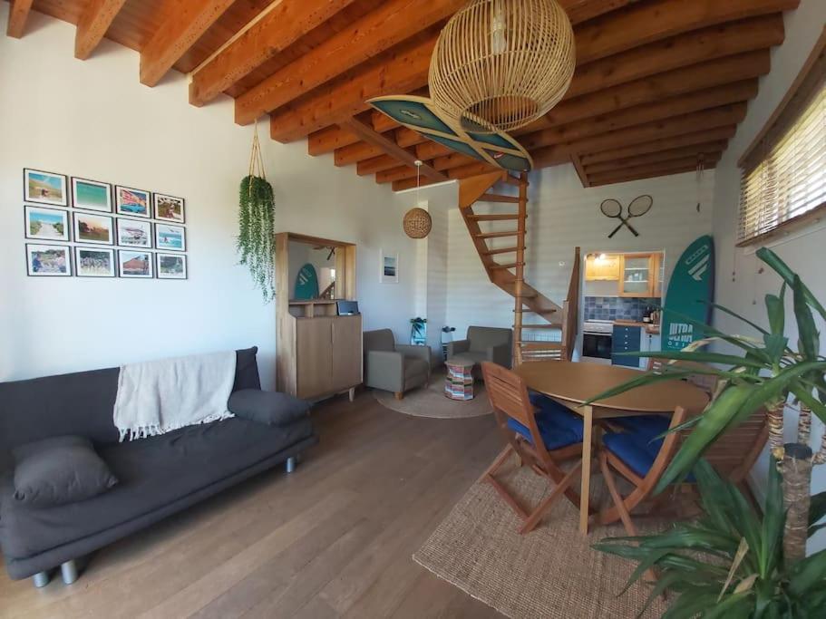 a living room with a table and a spiral staircase at Wissant, petite maison avec jardin proche mer in Wissant