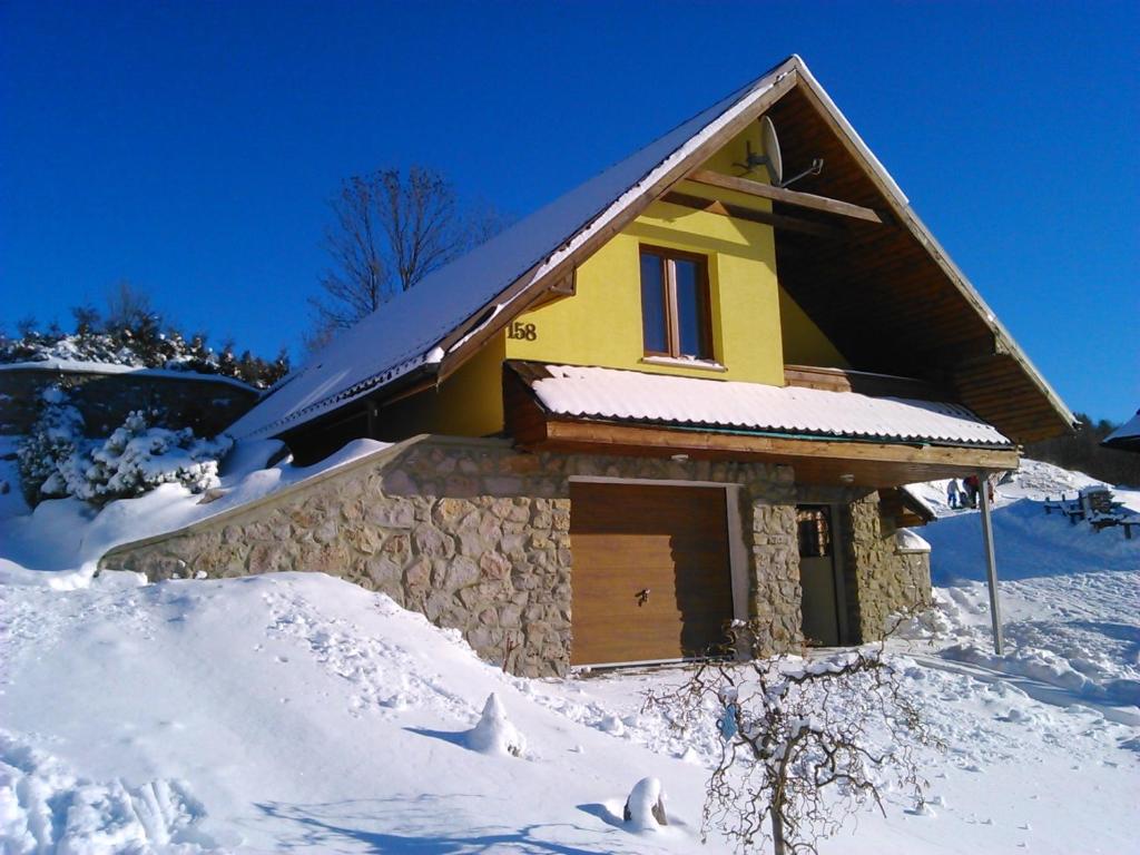 uma casa amarela com uma porta na neve em Víkendový Dom U Vasila em Krahule