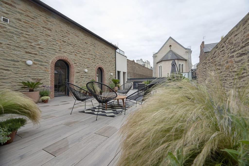 un patio avec des chaises et une table et un bâtiment dans l'établissement Le Standing Vasselot, à Rennes