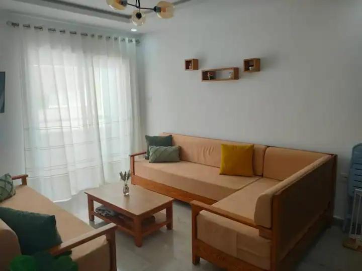 a living room with a couch and a coffee table at Apprt Proche Plage - Bien equipé in Kelibia