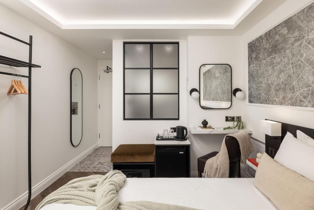 a bedroom with a bed and a desk and a mirror at St Giles London – A St Giles Hotel in London