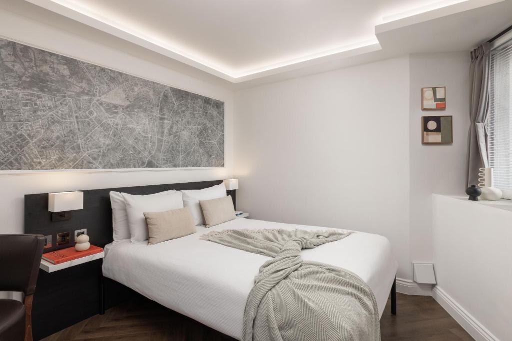 a bedroom with a large white bed and a table at St Giles London – A St Giles Hotel in London