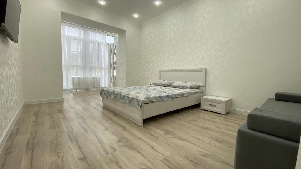 a white bedroom with a bed and a couch at Уютная 1-ком кв в Жк Альтаир мкр Батыс-2 in Aktobe