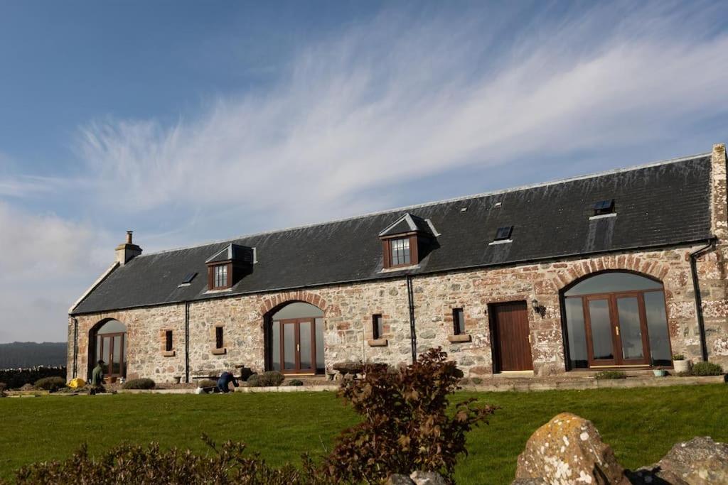 a stone house with a black roof at Balvraid Steading - Awesome views, near Dornoch in Dornoch