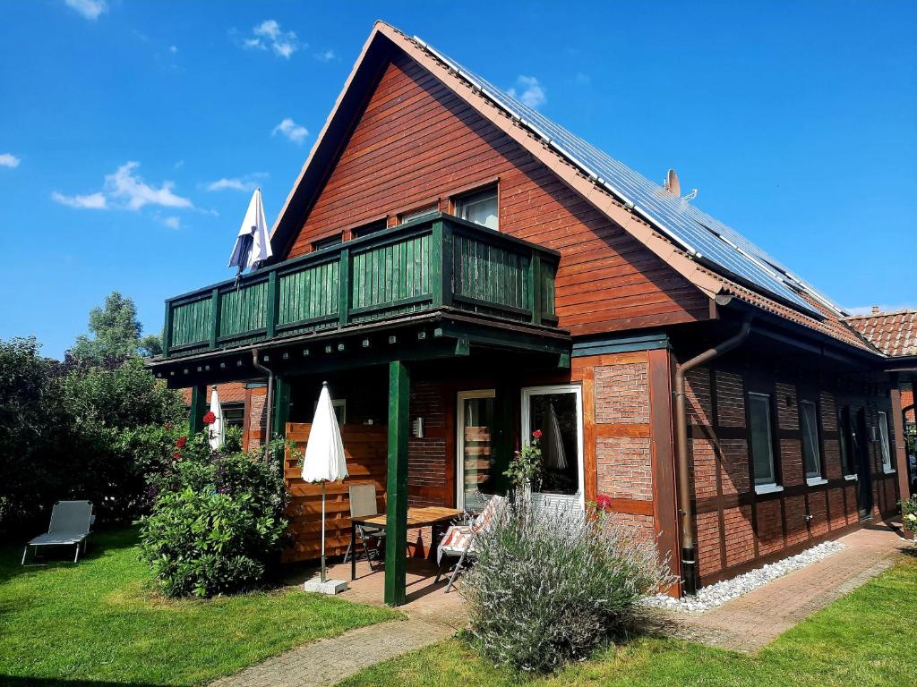 a wooden house with a balcony and a table at Ferienhaus Sasse Ferienwohnungen mit Garten & Grill in Mölschow