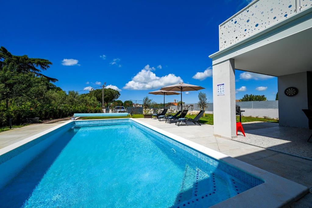 een zwembad met stoelen en een parasol bij Casa Ferata in Kanfanar