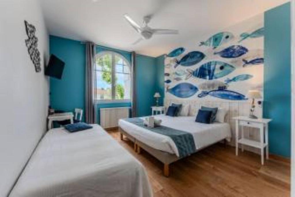 two beds in a room with blue walls at Hôtel Le Grain de Sable in Arès