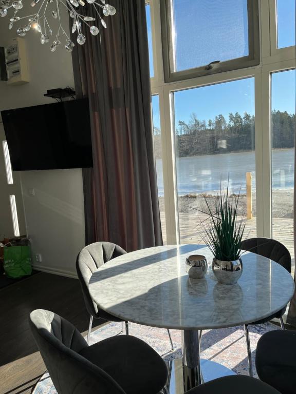 a table and chairs in a room with a large window at Beach Solsa in Nynäshamn