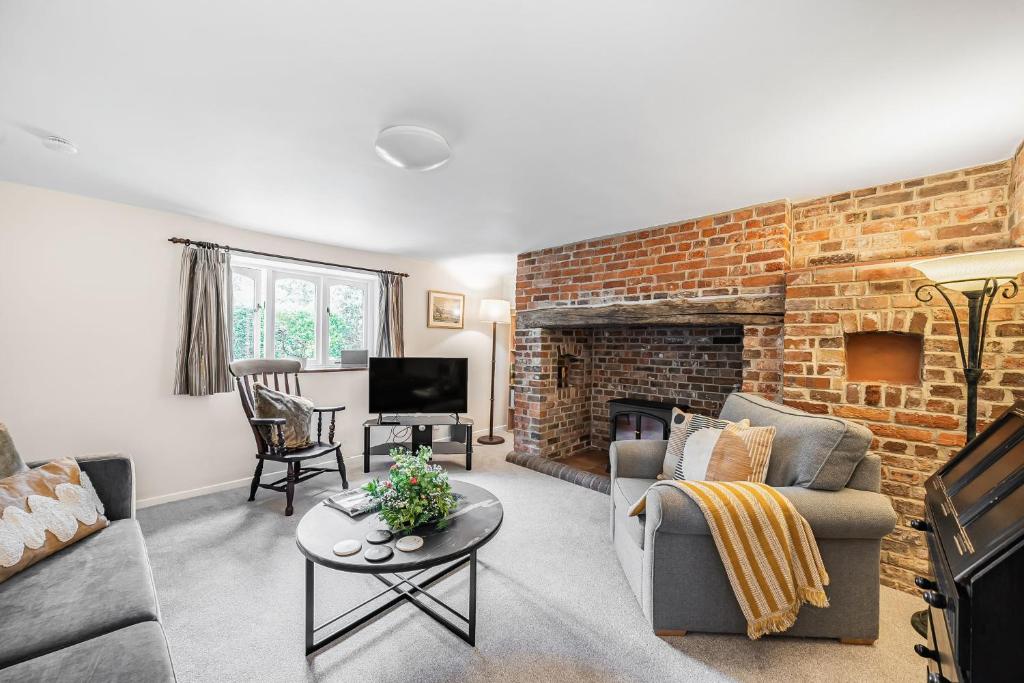 a living room with a couch and a brick wall at Chapel Cottage in Winterborne Kingston