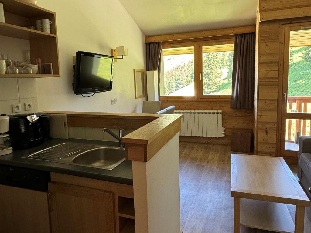 Il comprend une cuisine avec un évier et une télévision murale. dans l'établissement Duplex cosy à Belle Plagne - Ski aux pieds, balcon, piscine, bien-être, animaux admis - FR-1-181-2821, à La Plagne Tarentaise