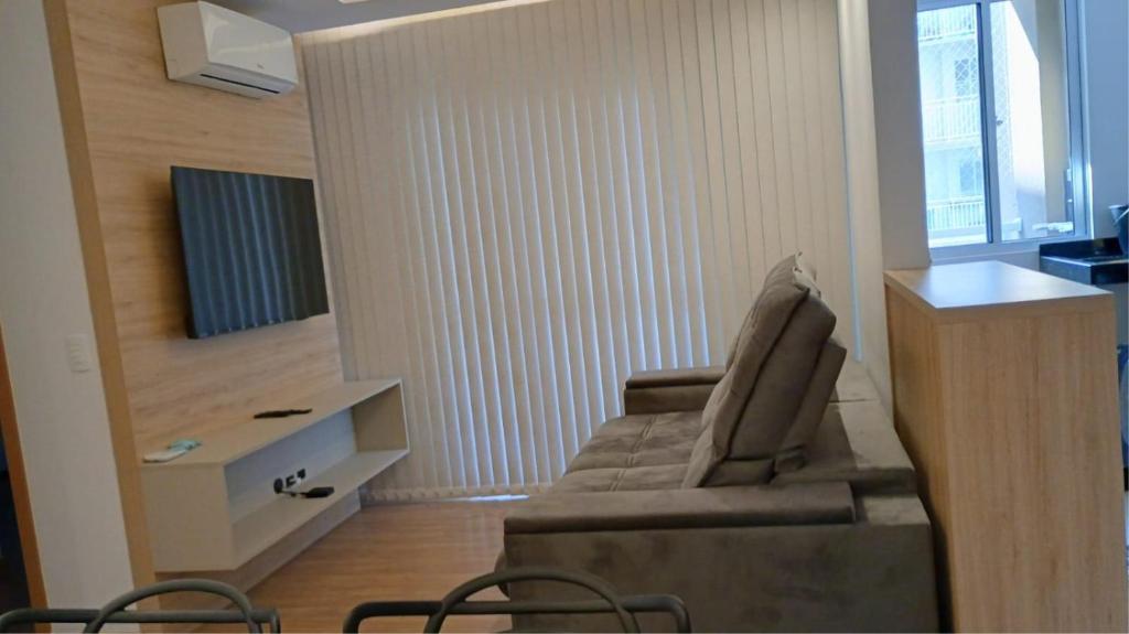 a living room with a couch and a television at Apartamento em Condomínio Frente Mar Barra Velha-SC in Barra Velha