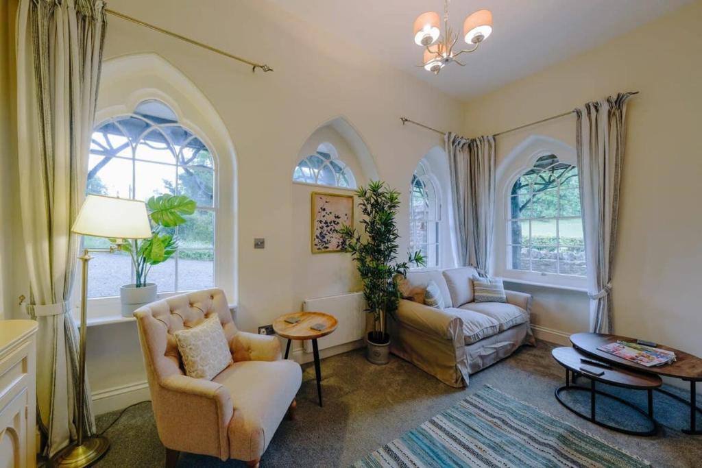 a living room with a couch and chairs and windows at The Lodge Gatehouse at Coombe Lodge in Bristol