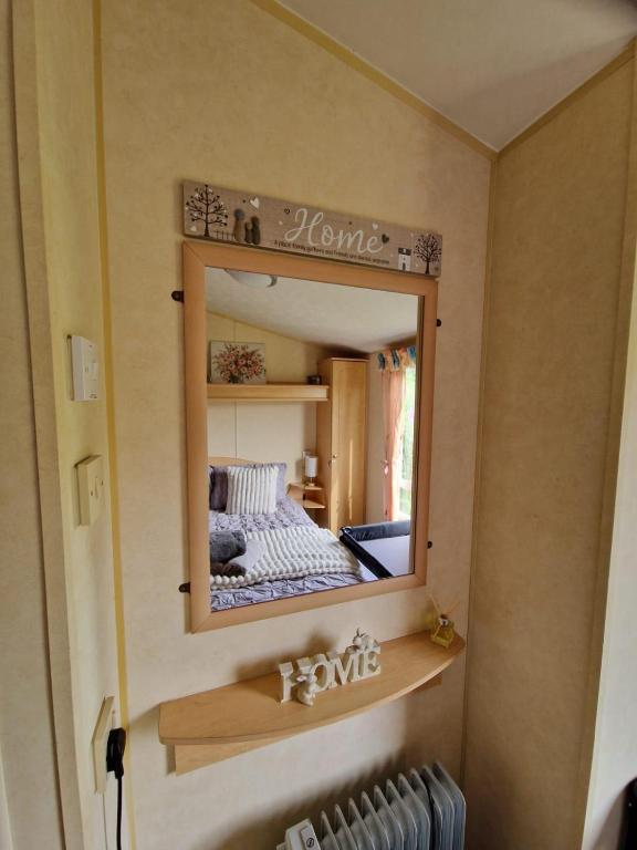 a mirror on a wall with a bed in a room at Lochview Retreat Caravan in Balminnoch