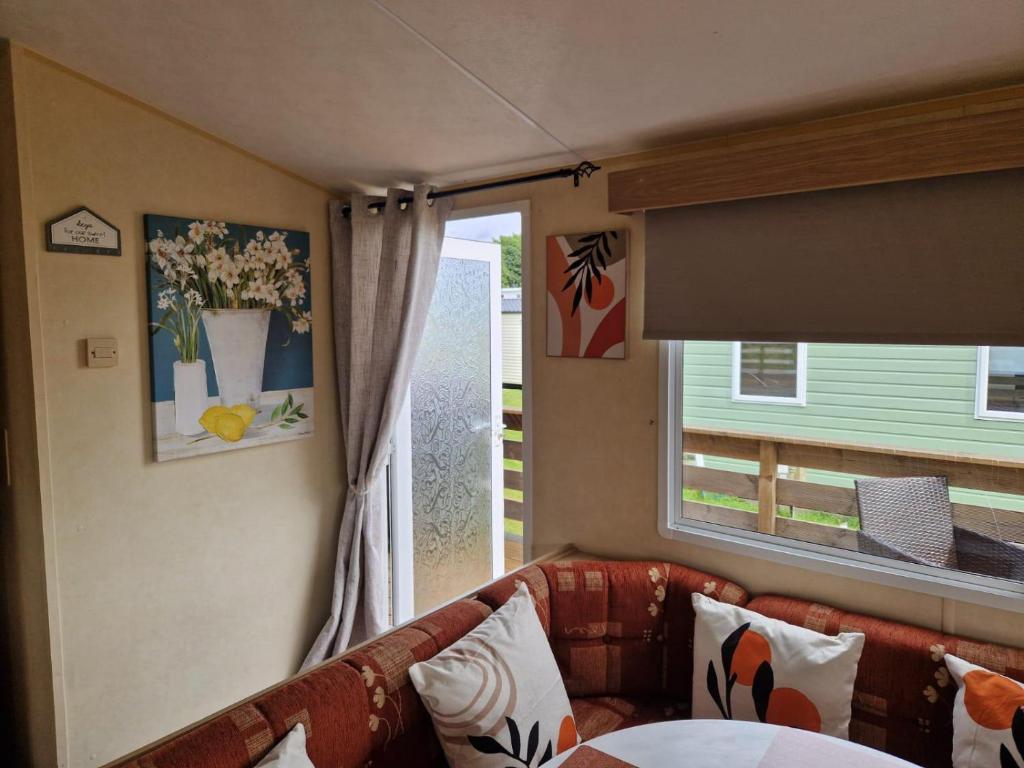 a living room with a couch and a window at Lochview Retreat Caravan in Balminnoch