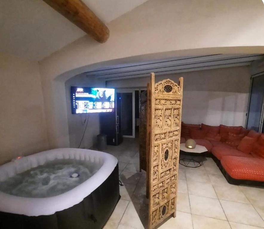d'un salon avec une grande baignoire et un canapé. dans l'établissement T2 PATIO avec jacuzzi et PISCINE 100m2 au pied du Luberon, à Cheval-Blanc