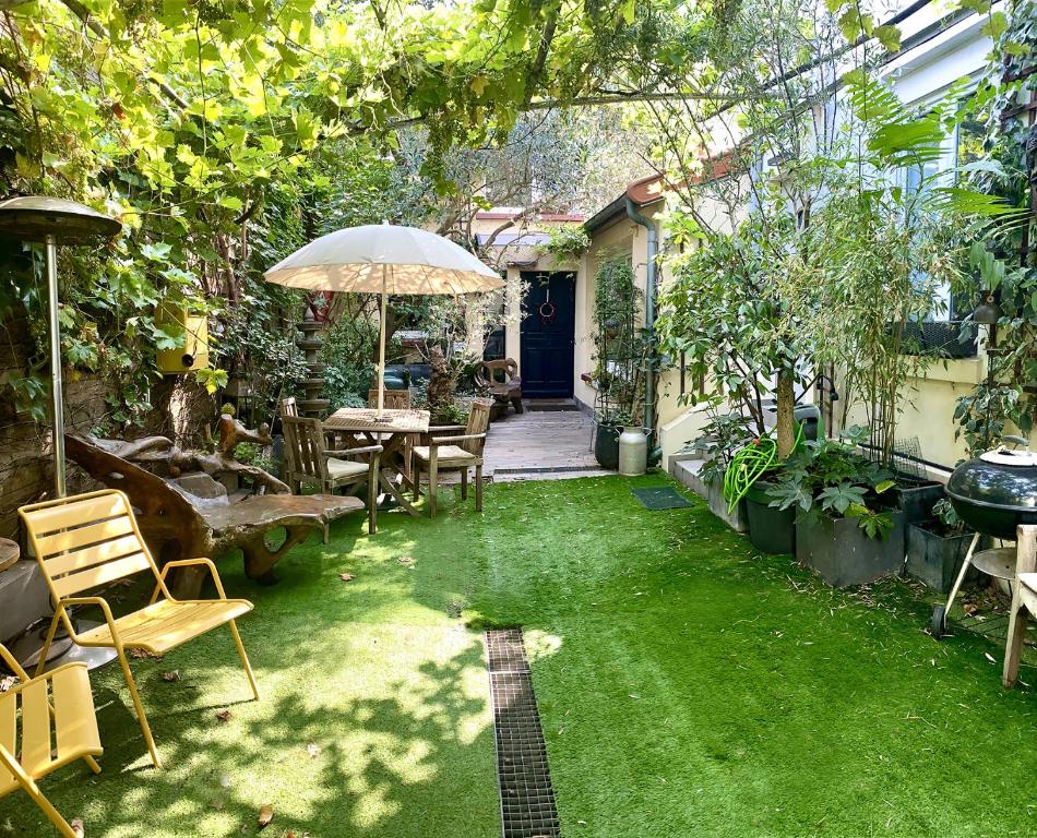 - un jardin avec une table, des chaises et un parasol dans l'établissement Jolie maison Parisienne Jardin Porte de Montreuil, à Bagnolet