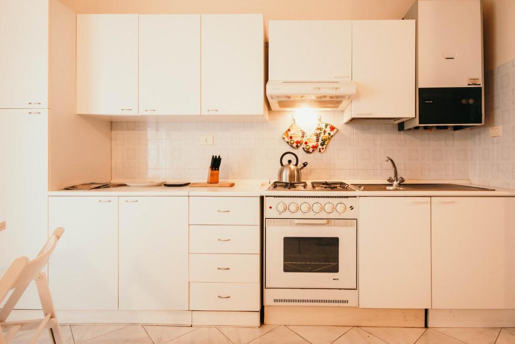 - une cuisine blanche avec des placards blancs et une cuisinière dans l'établissement L'Ulivo - Lakeside L&B, à Marinella di Sarzana