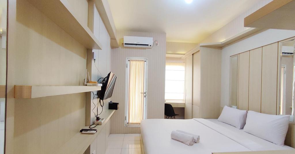 Un dormitorio con una cama blanca y un televisor. en Comfort Studio at Candiland Apartment By Travelio, en Semarang