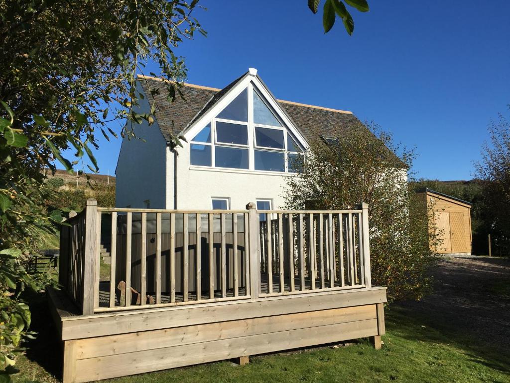 a wooden bench in front of a house at Windyhill Cottage in Achiltibuie