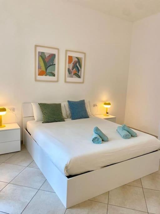 a white bed in a white room with two lamps at Appartamento Giardino e Parcheggio in Borgio Verezzi
