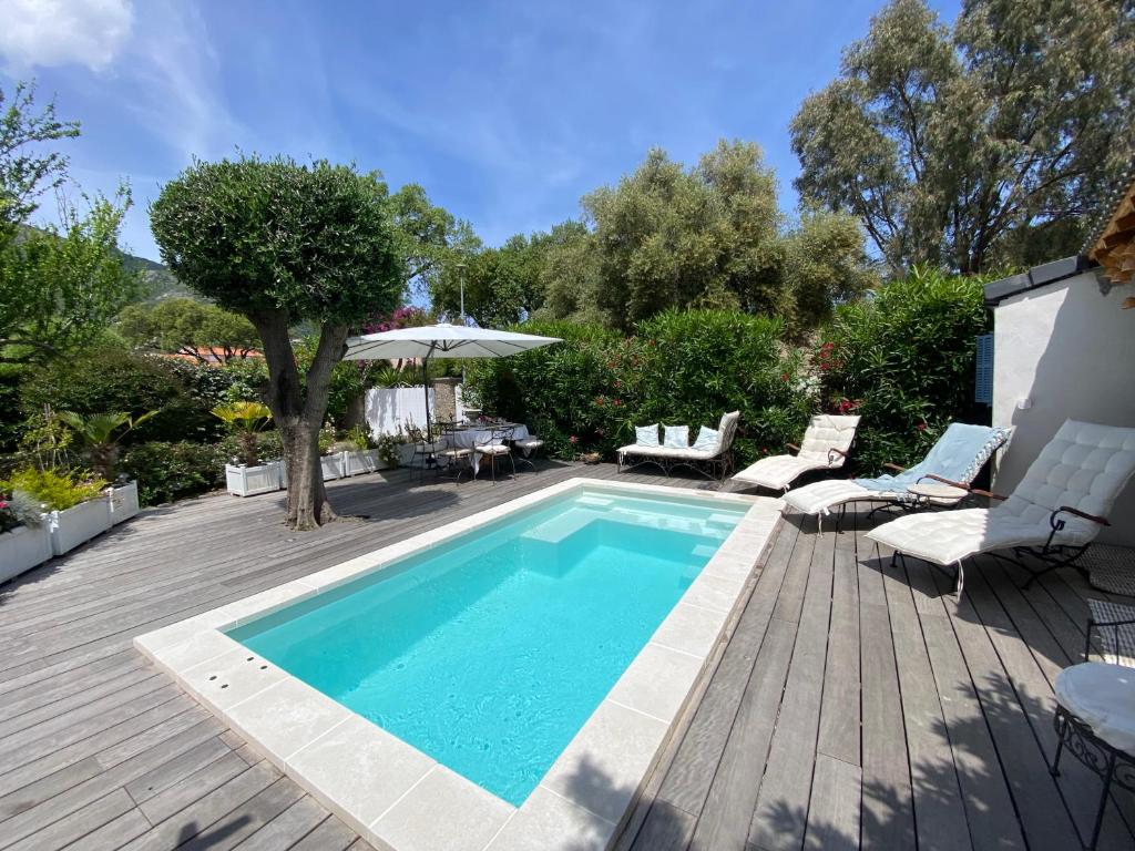 - une piscine sur une terrasse en bois avec des chaises et une table dans l'établissement La villa Flamingo toute proche de la plage, à Biguglia