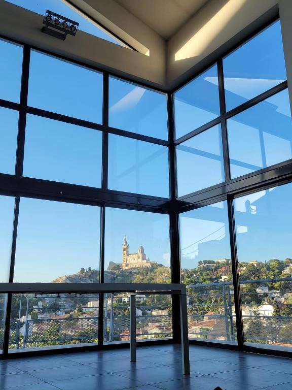Cette chambre dispose de grandes fenêtres offrant une vue sur un bâtiment. dans l'établissement Luxueux duplex avec vue panoramique sur Notre-Dame, à Marseille