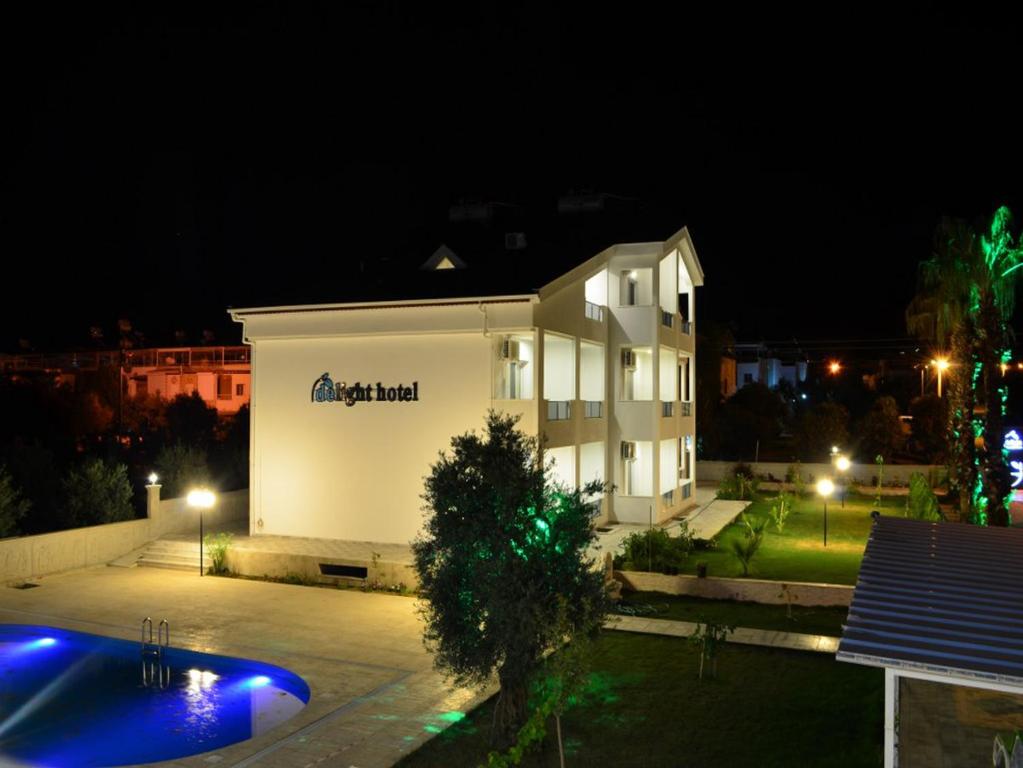 a building at night with a pool in front of it at Delight Boutique Hotel in Akbük