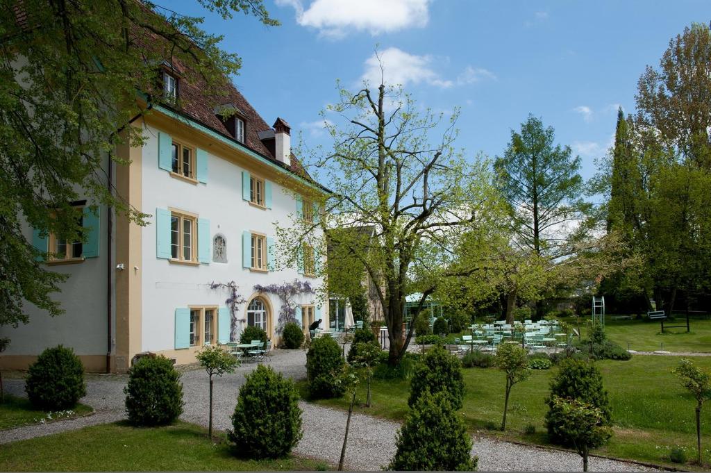 ein großes weißes Haus mit Bäumen und Sträuchern in der Unterkunft Schloss Ueberstorf - Tafeln, Tagen, Träumen in Ueberstorf