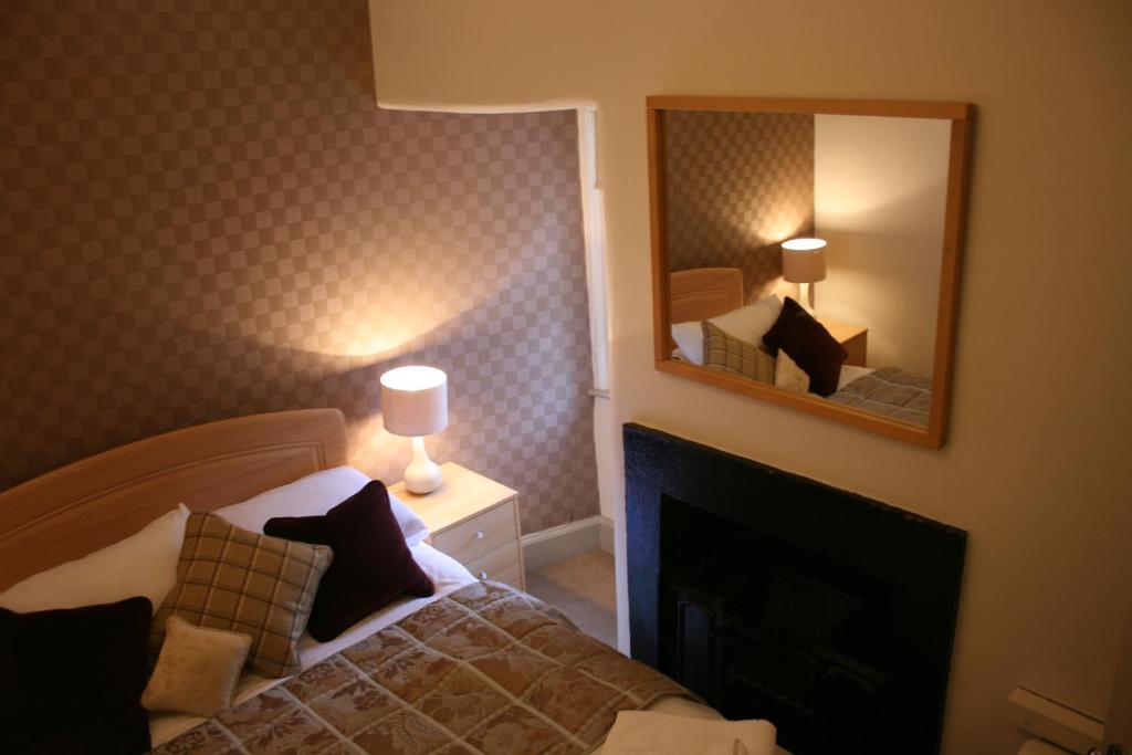 1 dormitorio con 1 cama con chimenea y espejo en Royal Mile Budget Apartments, en Edimburgo