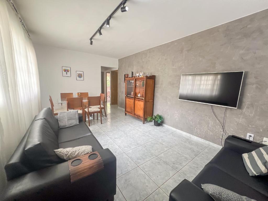 a living room with a black couch and a television at Apartamento VIP Centro Serra Negra - Familiar in Serra Negra