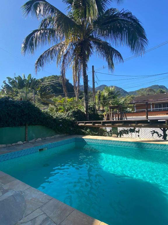 a swimming pool with a palm tree in the background at Brisa Maresias in Maresias