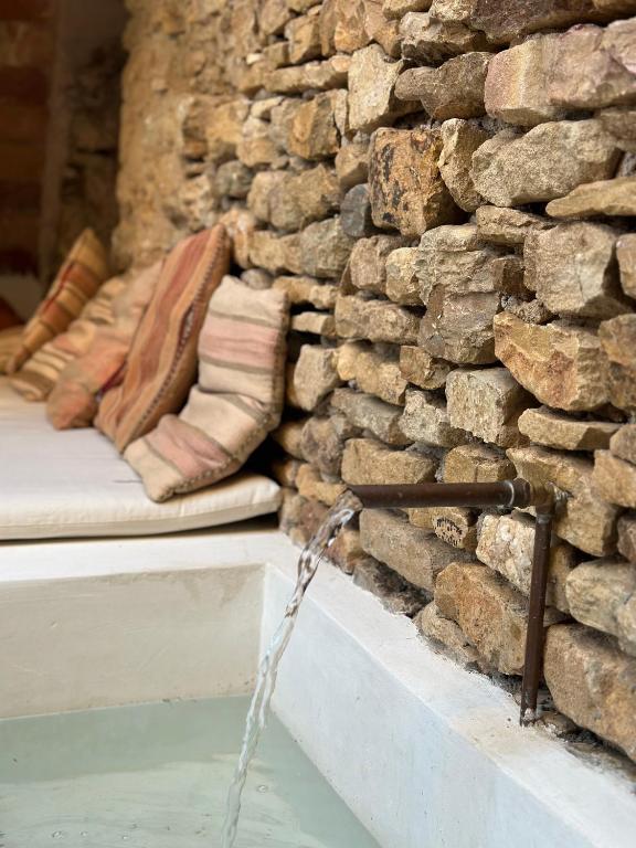 a water fountain in front of a stone wall at Can Casellas in Palau Sator