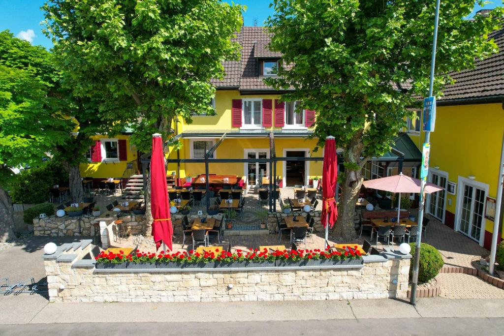 ein Restaurant mit roten Sonnenschirmen und Blumen vor einem Gebäude in der Unterkunft Tuniberg Restaurant Hotel in Freiburg im Breisgau