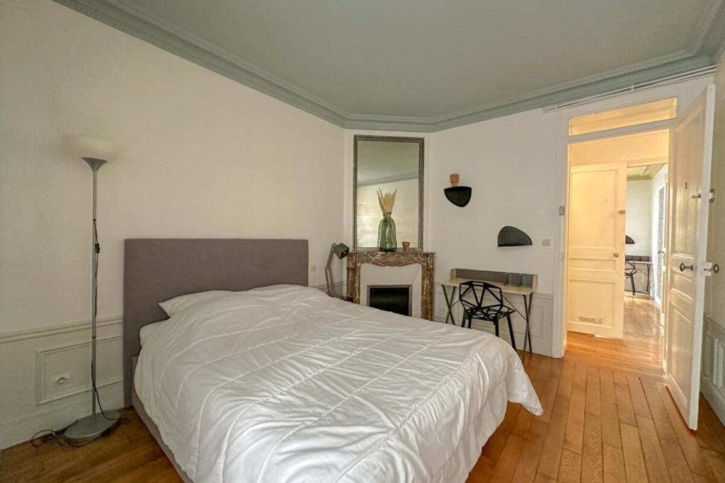une chambre avec un grand lit blanc et une table dans l'établissement Flexliving - room - Bachaumont, à Paris