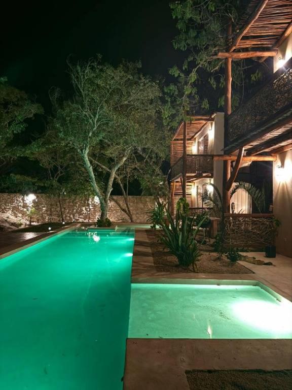 a swimming pool in front of a house at night at Villa Natural en Chemuyil in Balcheil