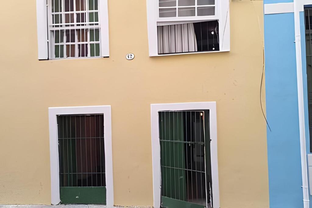 a building with two green doors and two windows at CENTRO DO PELOURINHO in Salvador
