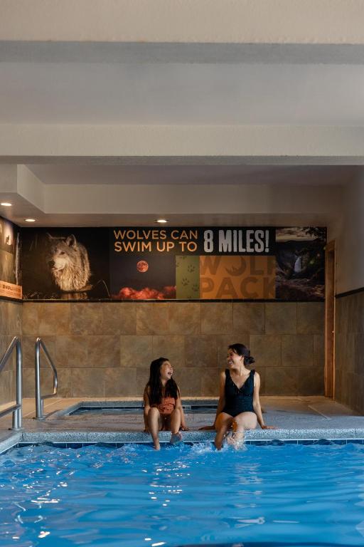 two women sitting on the edge of a swimming pool at Gray Wolf Inn &amp; Suites in West Yellowstone