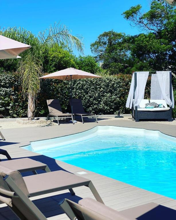 a swimming pool with lounge chairs and umbrellas next to at Hotel l'Isolella in Porticcio