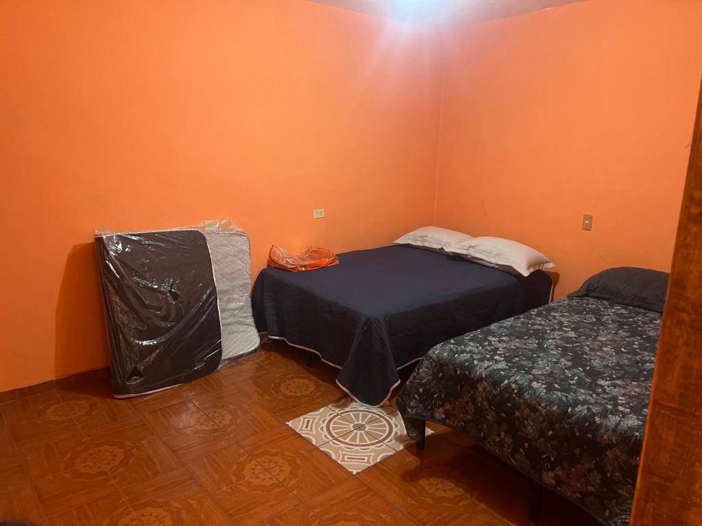two beds in a room with orange walls at Casa Socorro in Tala