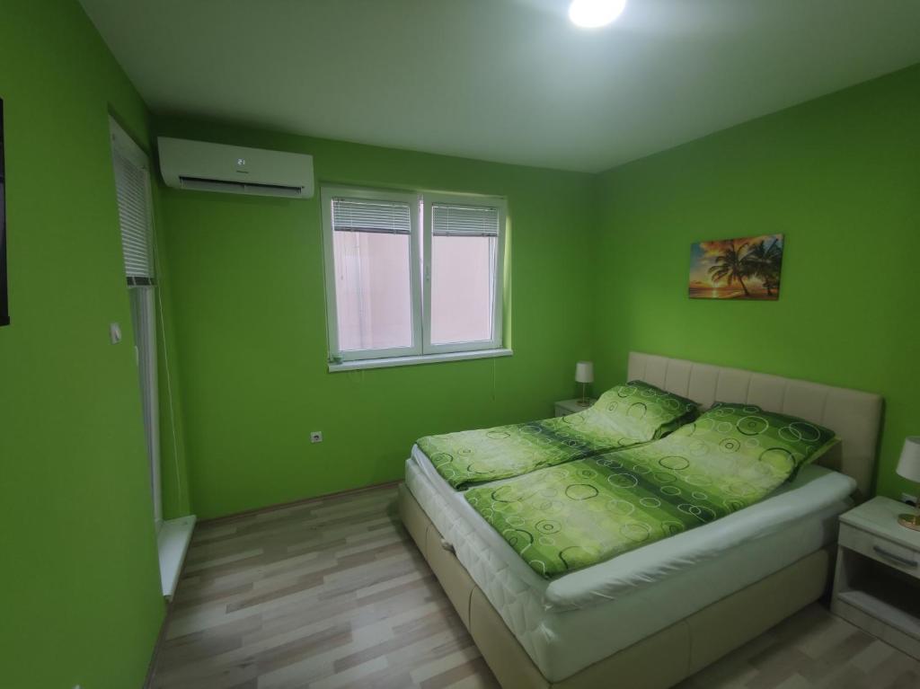 a green bedroom with a bed and a window at Apartman Kaoma in Soko Banja