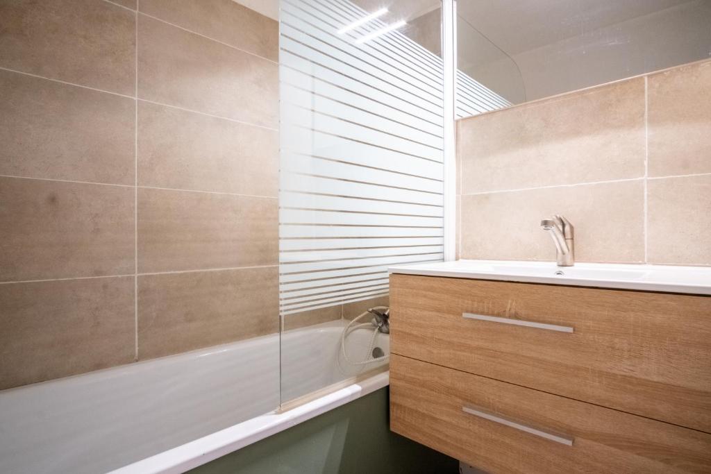 W łazience znajduje się prysznic, umywalka i wanna. w obiekcie Appartement cosy 1 chambre 4 pers face pistes 08 w mieście LʼHuez