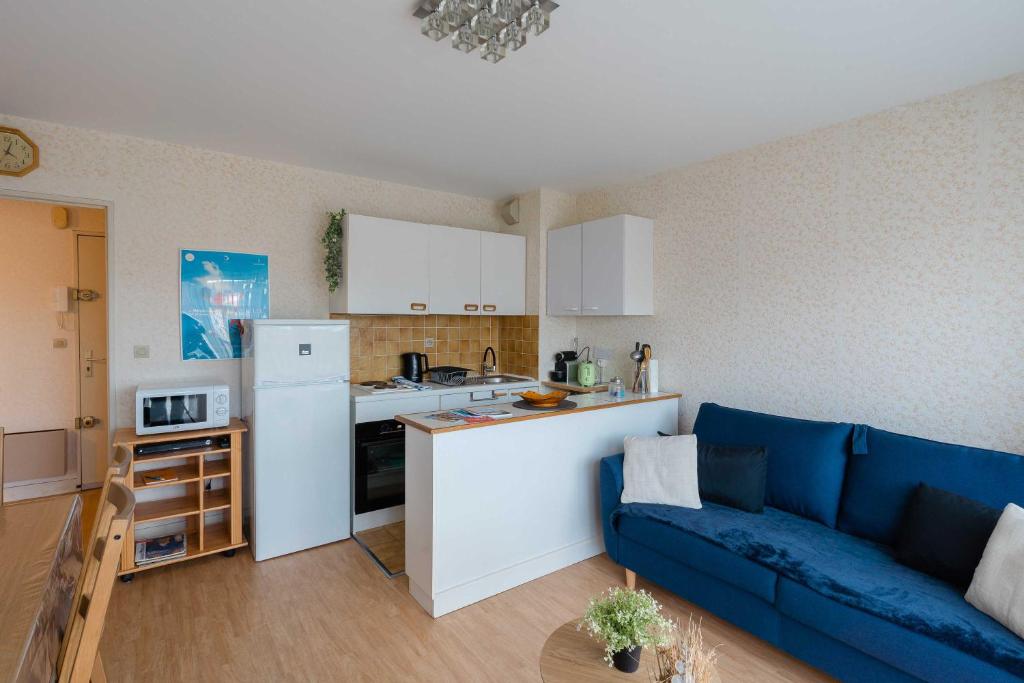 Il comprend une cuisine et un salon avec un canapé bleu. dans l'établissement Charming apartment with parking near Place Morny, à Deauville