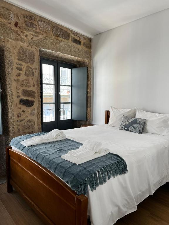 a bedroom with a large bed with a brick wall at Casa Dentro da Vila in Ponte de Lima
