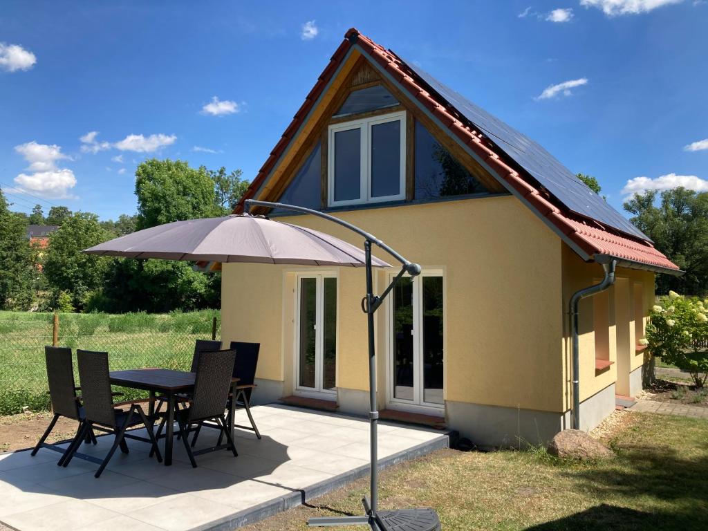 a house with a table and chairs and an umbrella at Zum Ilmwinkel in Bad Sulza