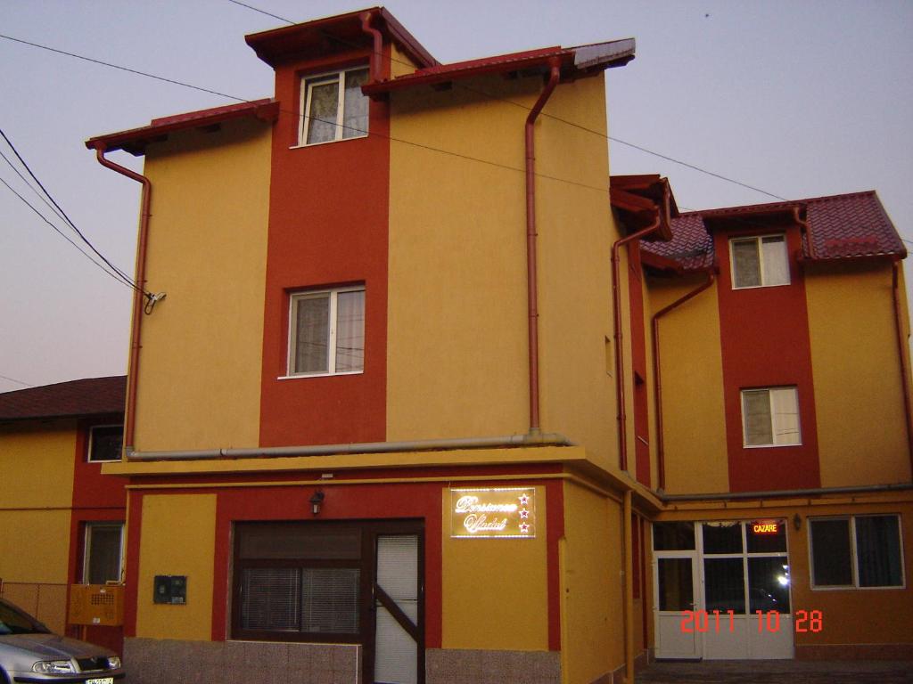 ein großes gelbes und rotes Haus mit Garage in der Unterkunft Pensiunea Vladut Timisoara in Timişoara