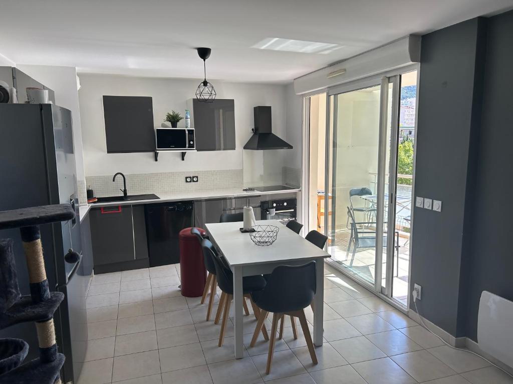 une cuisine avec une table et des chaises et une cuisine avec vue dans l'établissement Charmant T3 proche gare et plages Toulon PARKING PRIVÉ, à Toulon
