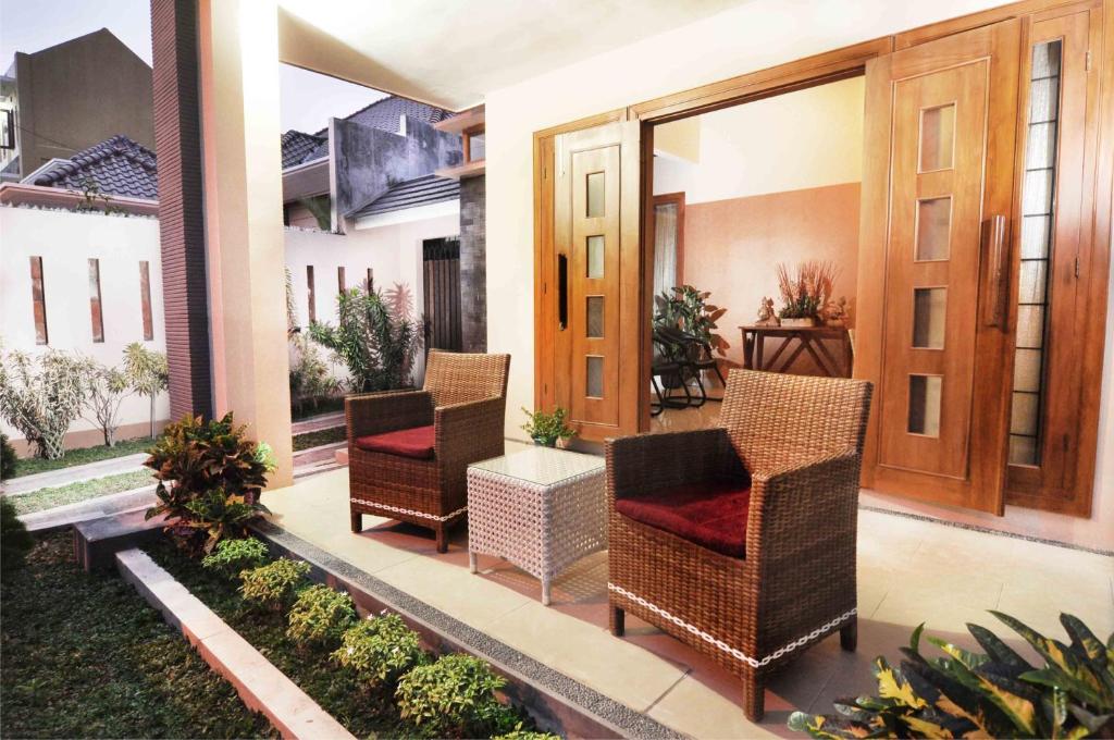 a porch with wicker chairs and a table at Batikan de Ville House in Yogyakarta